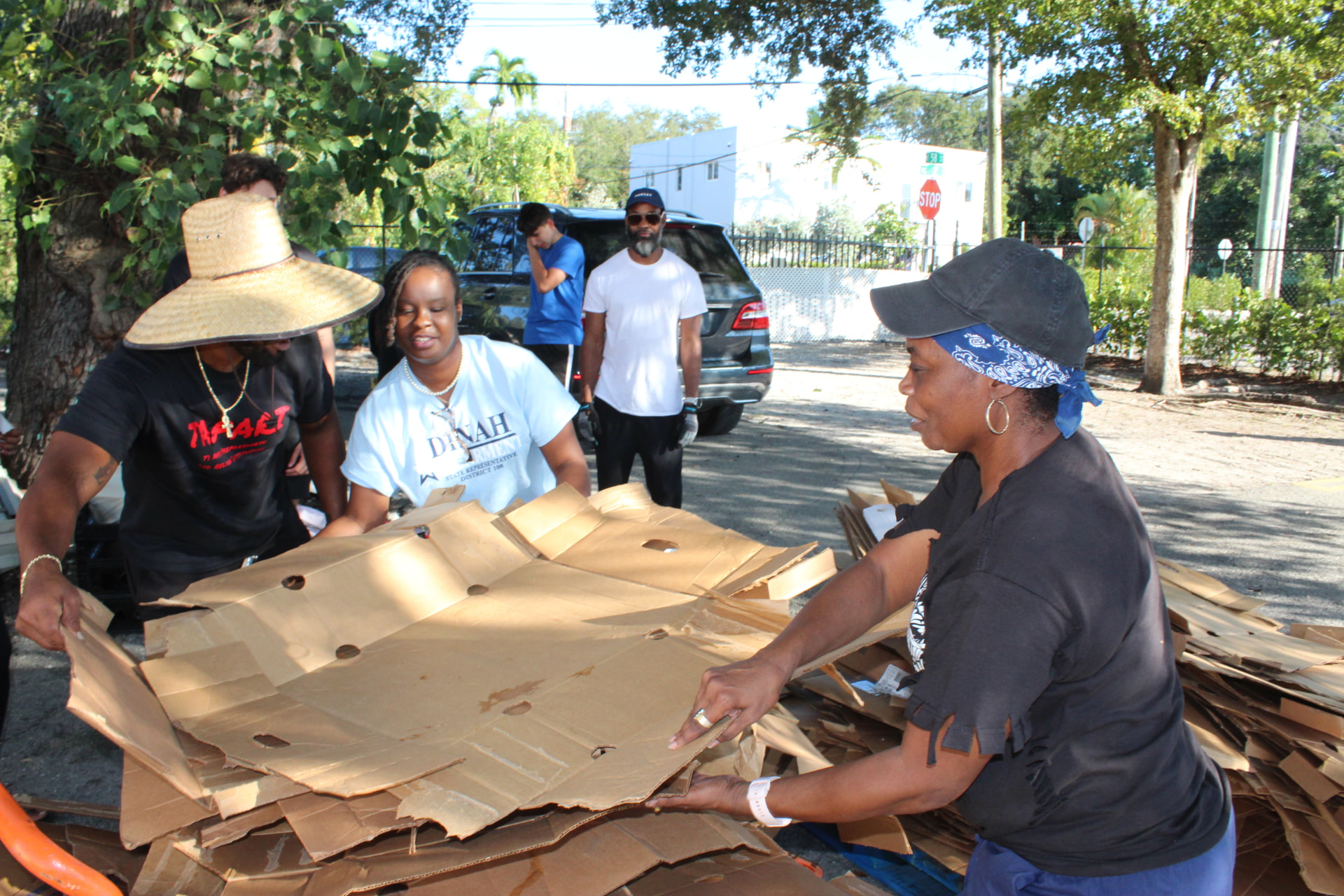 Volunteers gather and flatten cardboard boxes outdoors after a distribution.